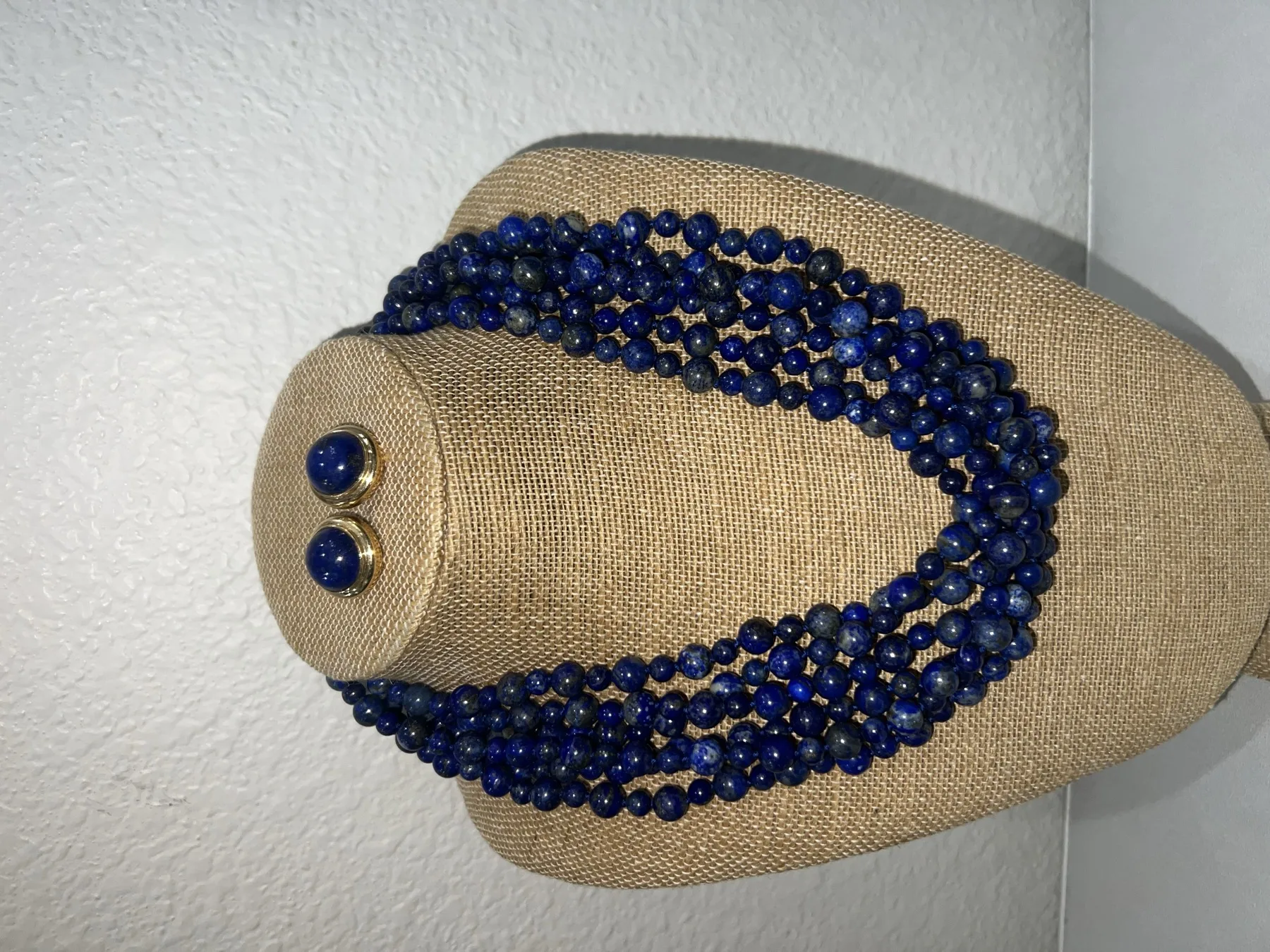 Layers of lapis jewelry displayed on a linen form